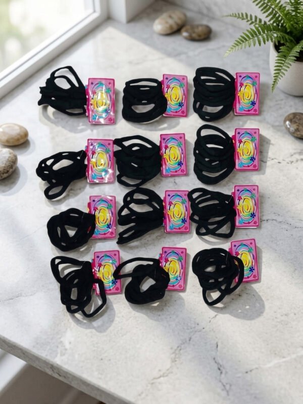 Muestra de 12 tarjetas de cartón con colitas elásticas negras para el cabello distribuidas en filas sobre fondo blanco.