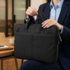 Funda portanotebook negra con manijas de mano sobre piso de madera